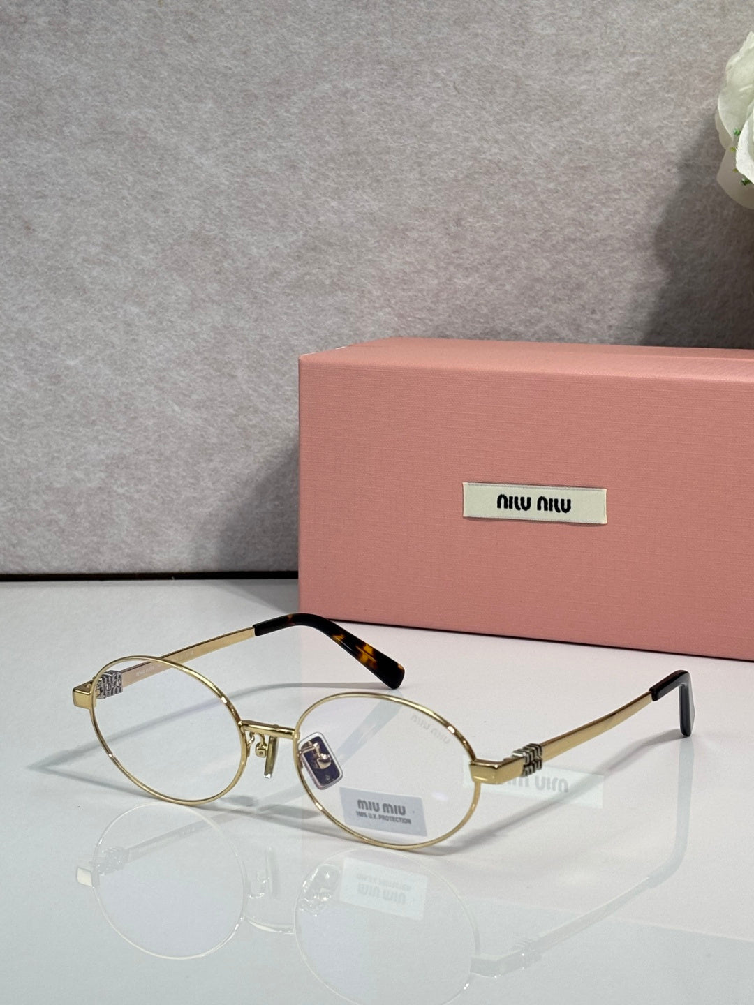 MiuMiu round eyeglasses with gold frame and clear lenses, tortoise-print temple detail