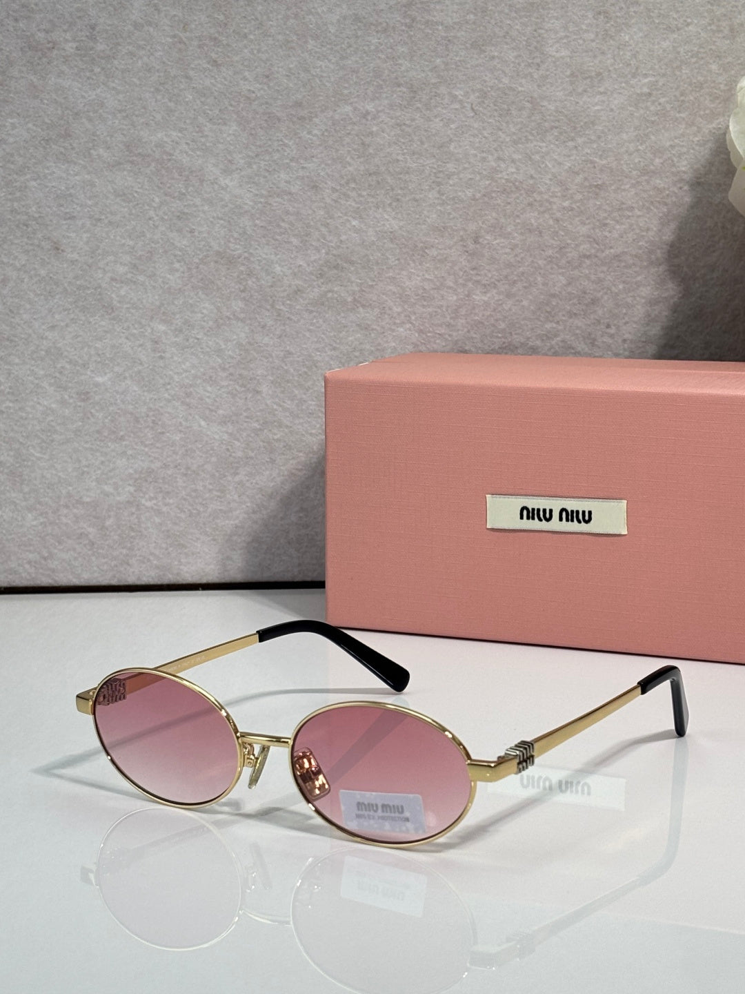 MiuMiu round sunglasses with gold frame and pink lenses, black temple tips