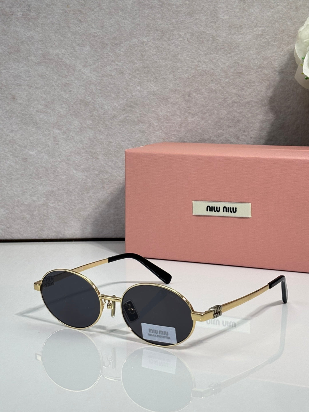 MiuMiu round sunglasses with gold frame and dark lenses, black temple tips