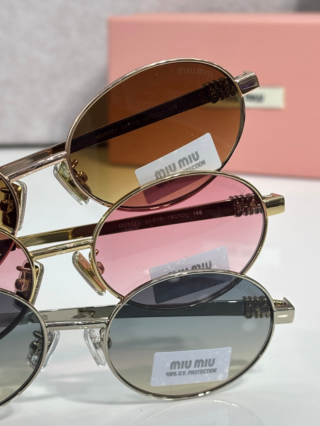 MiuMiu round sunglasses set with gold frames and tinted lenses, stamped logos on arms