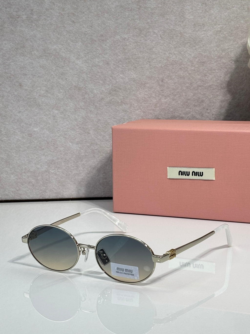 MiuMiu round sunglasses with gold frame and blue lenses, black temple detail