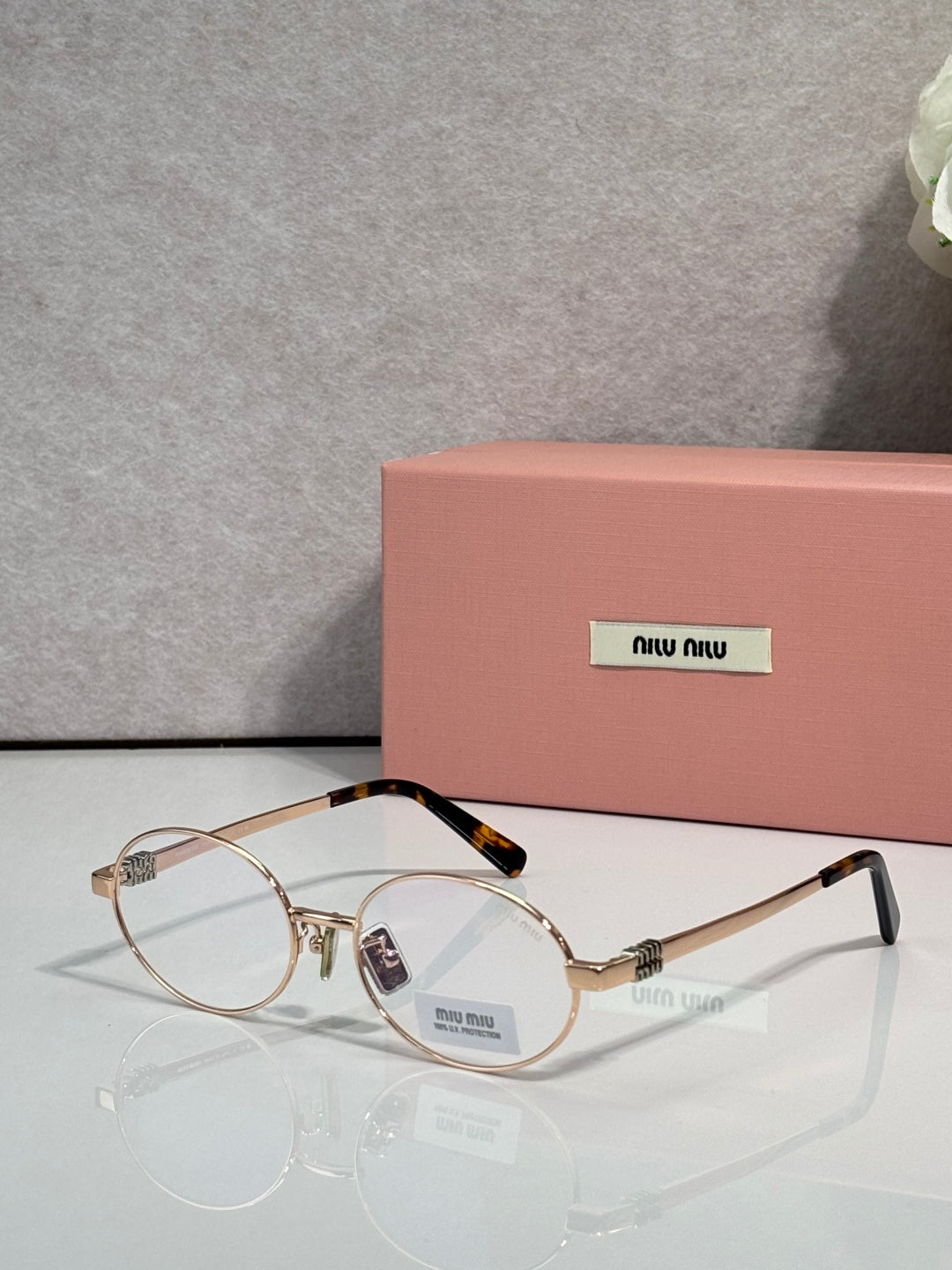 MiuMiu round eyeglasses with gold frame and clear lenses, black temple tips