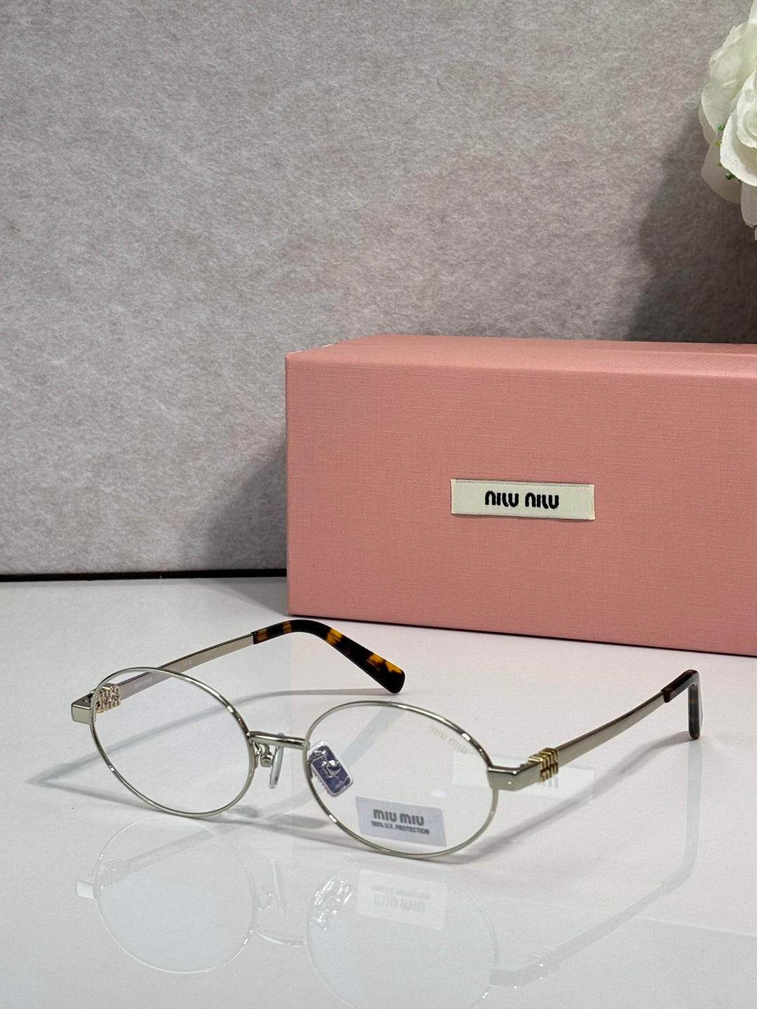 MiuMiu round eyeglasses with gold frame and clear lenses, black temple accents