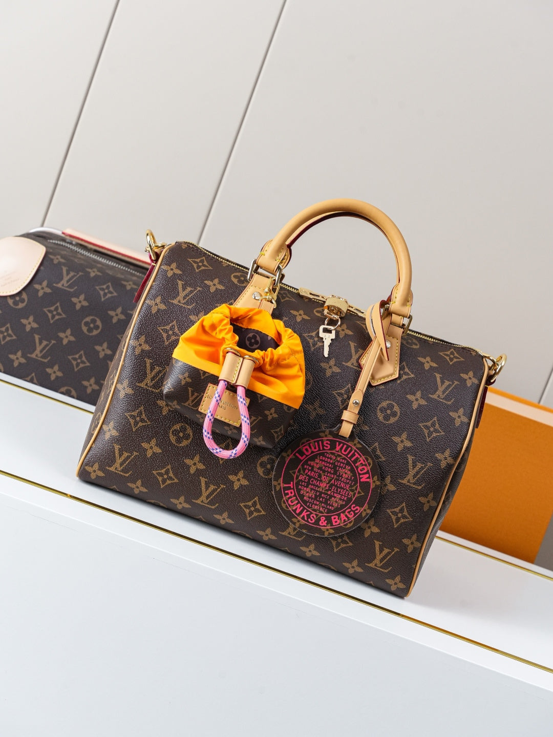 Louis Vuitton monogram canvas handbag with tan leather handles and orange charm detail