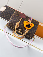 Louis Vuitton monogram canvas bag with tan handles and orange bow charm, plus crossbody strap