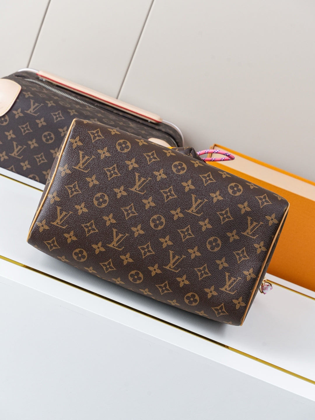 Louis Vuitton monogram canvas handbag with top zipper, tan trim, and colorful charm at handle