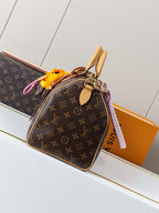 Louis Vuitton monogram canvas tote with tan leather handles, orange pouch charm, and strap tag