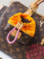 Louis Vuitton monogram canvas bag close-up with orange pouch charm and tan hardware