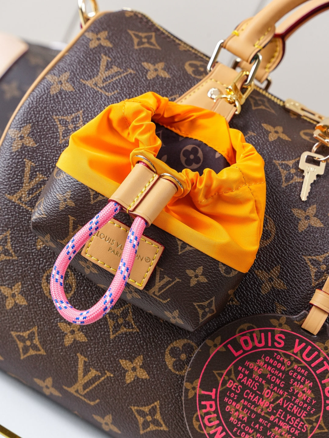 Louis Vuitton monogram canvas bag close-up with orange pouch charm and tan hardware
