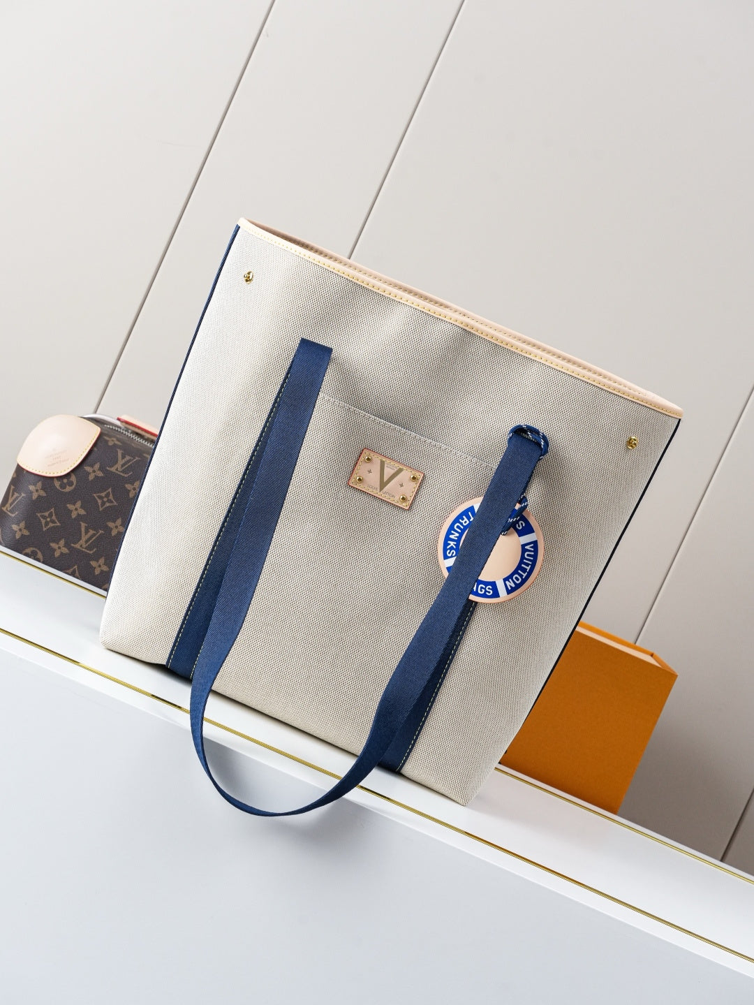 Beige canvas tote bag with navy striped handles and gold-tone hardware
