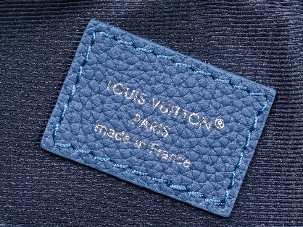 Blue leather brand label on crossbody bag with embossed text