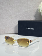 Sunglasses with clear frames, gold logo accents, and golden tinted lenses