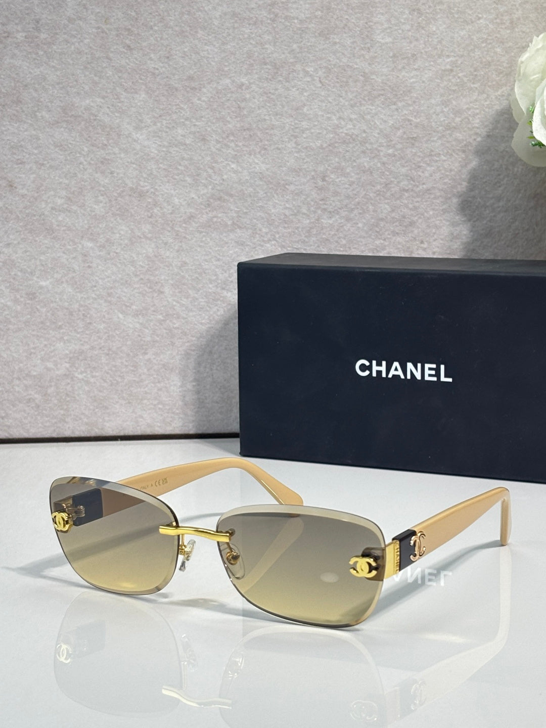 Sunglasses with light beige frames, gold logo accents, and amber tinted lenses