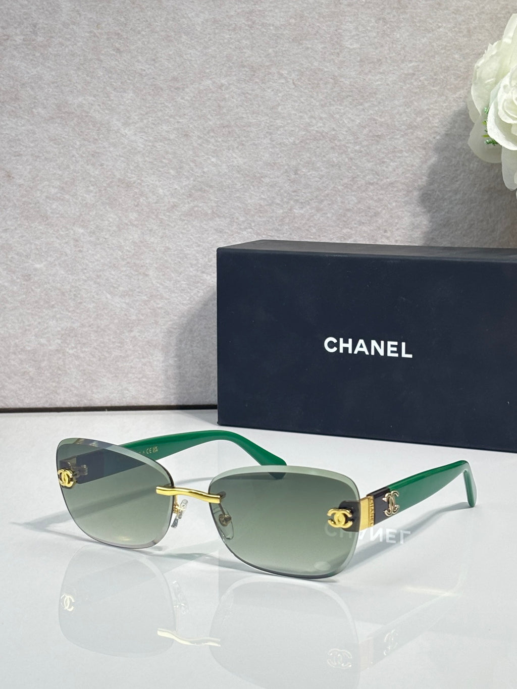 Sunglasses with green frames, gold logo accents, and muted green tinted lenses