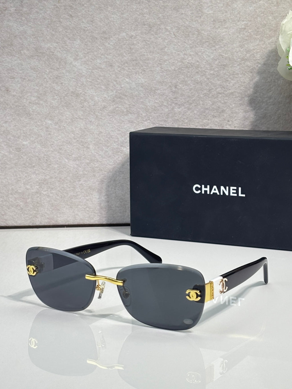 Sunglasses with dark blue frames, gold logo accents, and dark tinted lenses