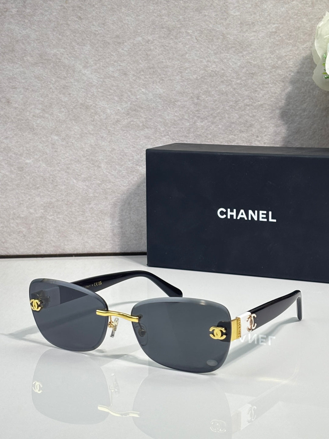 Sunglasses with dark blue frames, gold logo accents, and dark tinted lenses