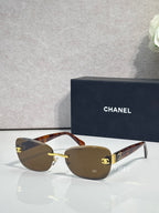 Sunglasses with tortoise-brown frames, gold logo accents, and dark tinted lenses