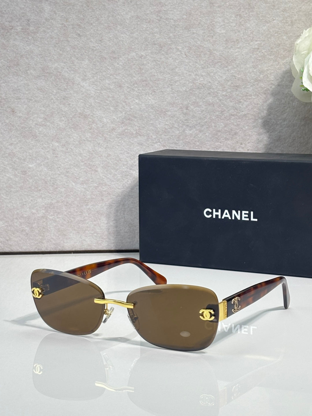Sunglasses with tortoise-brown frames, gold logo accents, and dark tinted lenses