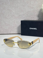 Chanel sunglasses with gold-tone frame and amber tinted lenses, beige temples