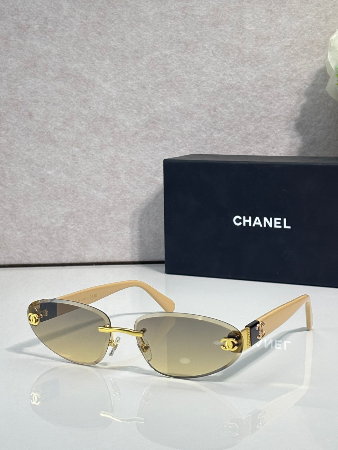 Chanel sunglasses with gold-tone frame and amber tinted lenses, beige temples