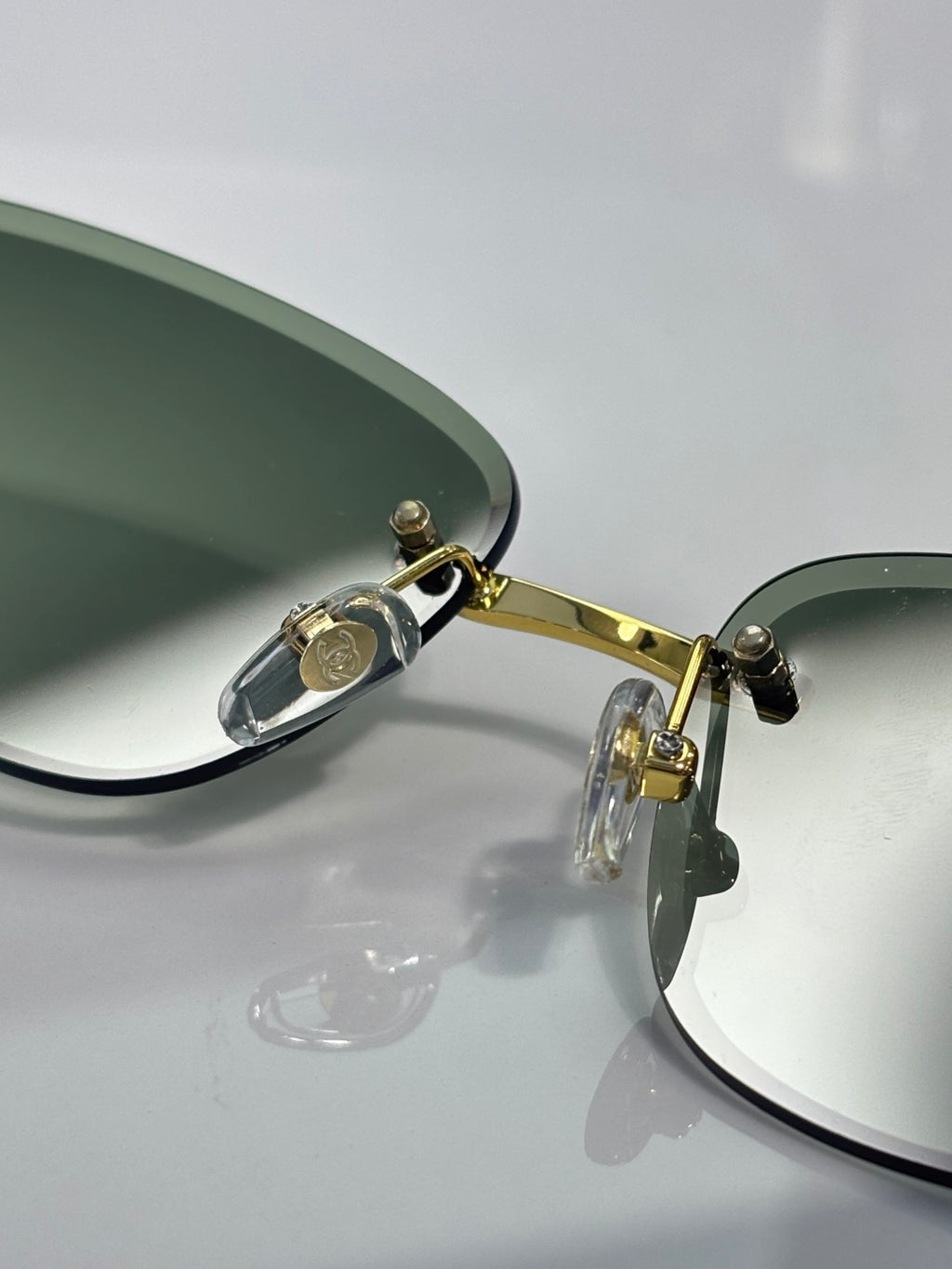Chanel sunglasses close-up of gold hinge and green-tinted lens edge