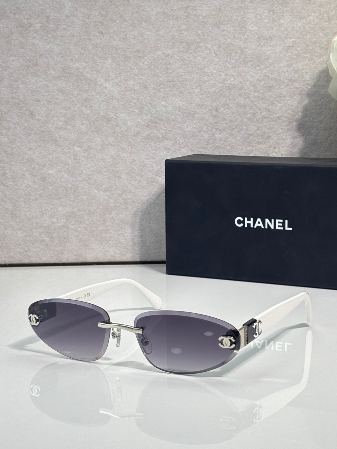 Chanel sunglasses with gold-tone frame and dark tinted lenses, white temples