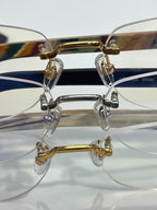 Eyeglass frame detail: clear lenses with gold and dark blue temple pieces