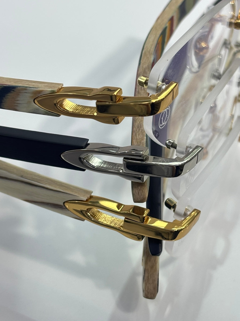 Eyeglass frame detail: gold and silver-tone temple arms with patterned wood-look panels