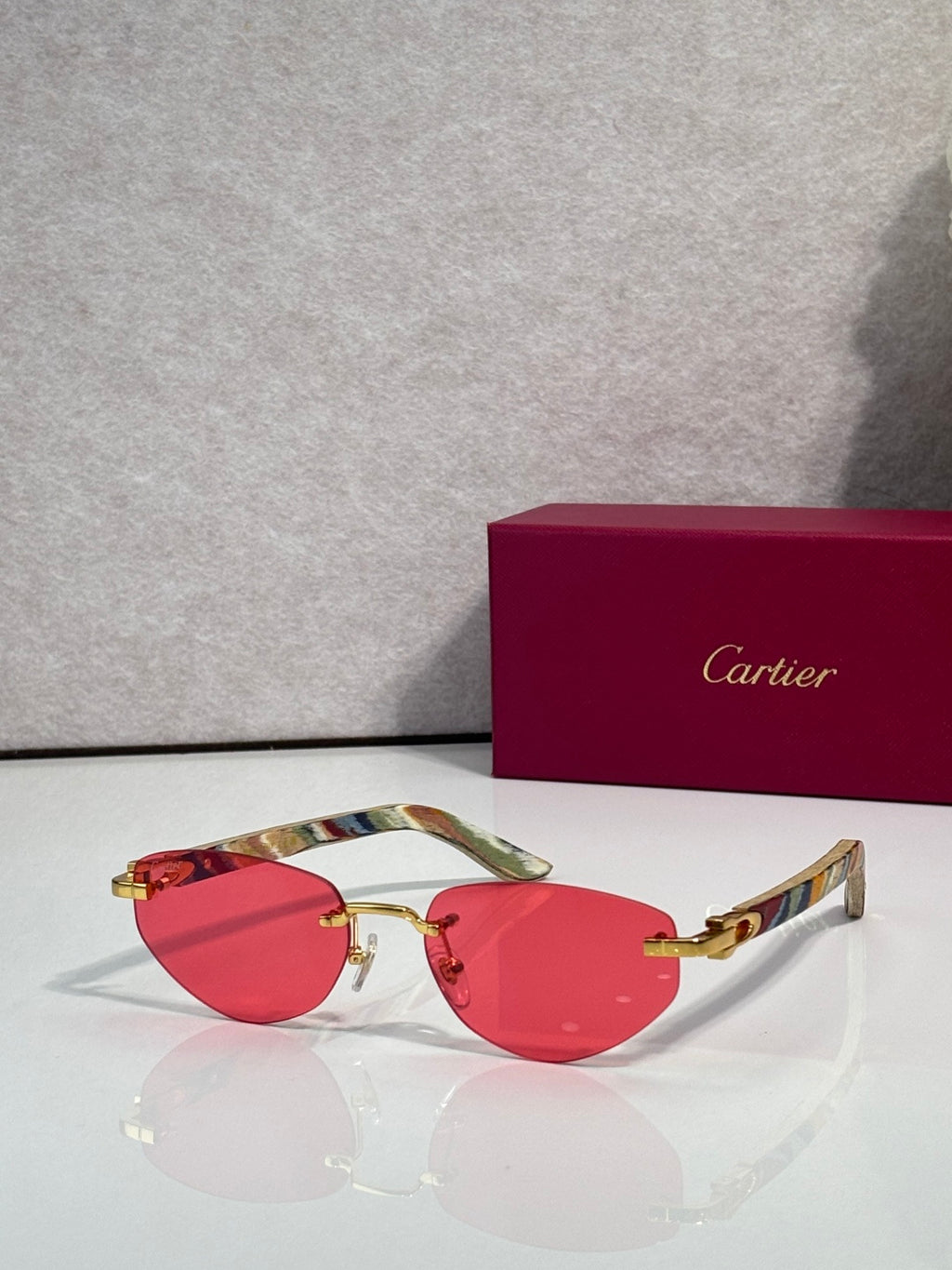 Cartier sunglasses with red tinted lenses and gold-tone frame, multicolor temples