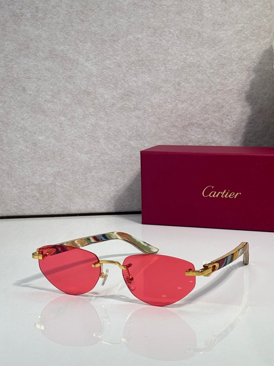 Cartier sunglasses with red tinted lenses and gold-tone frame, multicolor temples
