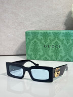 Rectangular dark sunglasses with light blue lenses and gold GG logo on temple