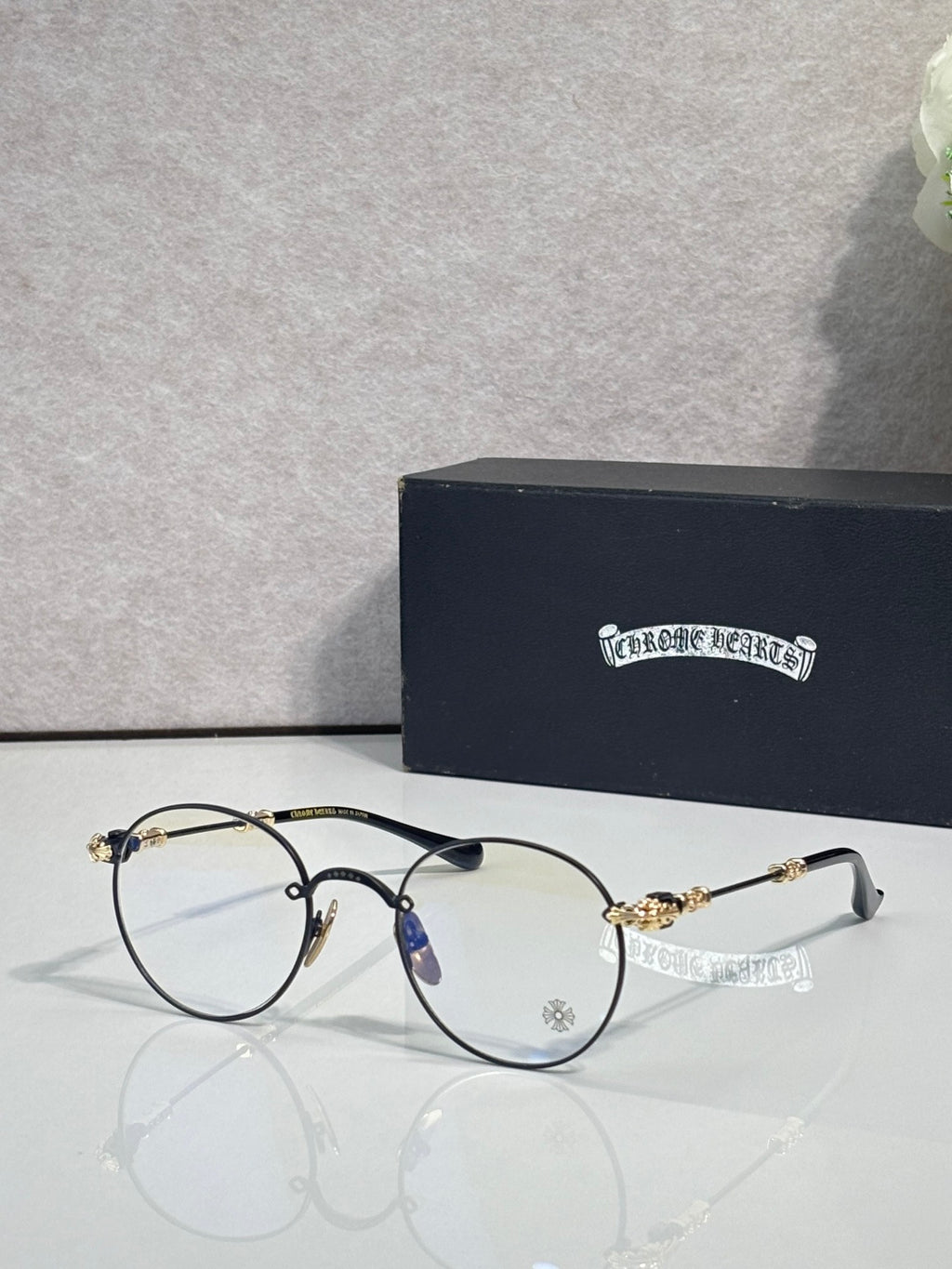 Round eyeglasses with dark blue frame and gold-tone ornate temples