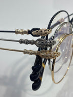 Round eyeglasses with dark blue temples and gold-tone ornate temple accents