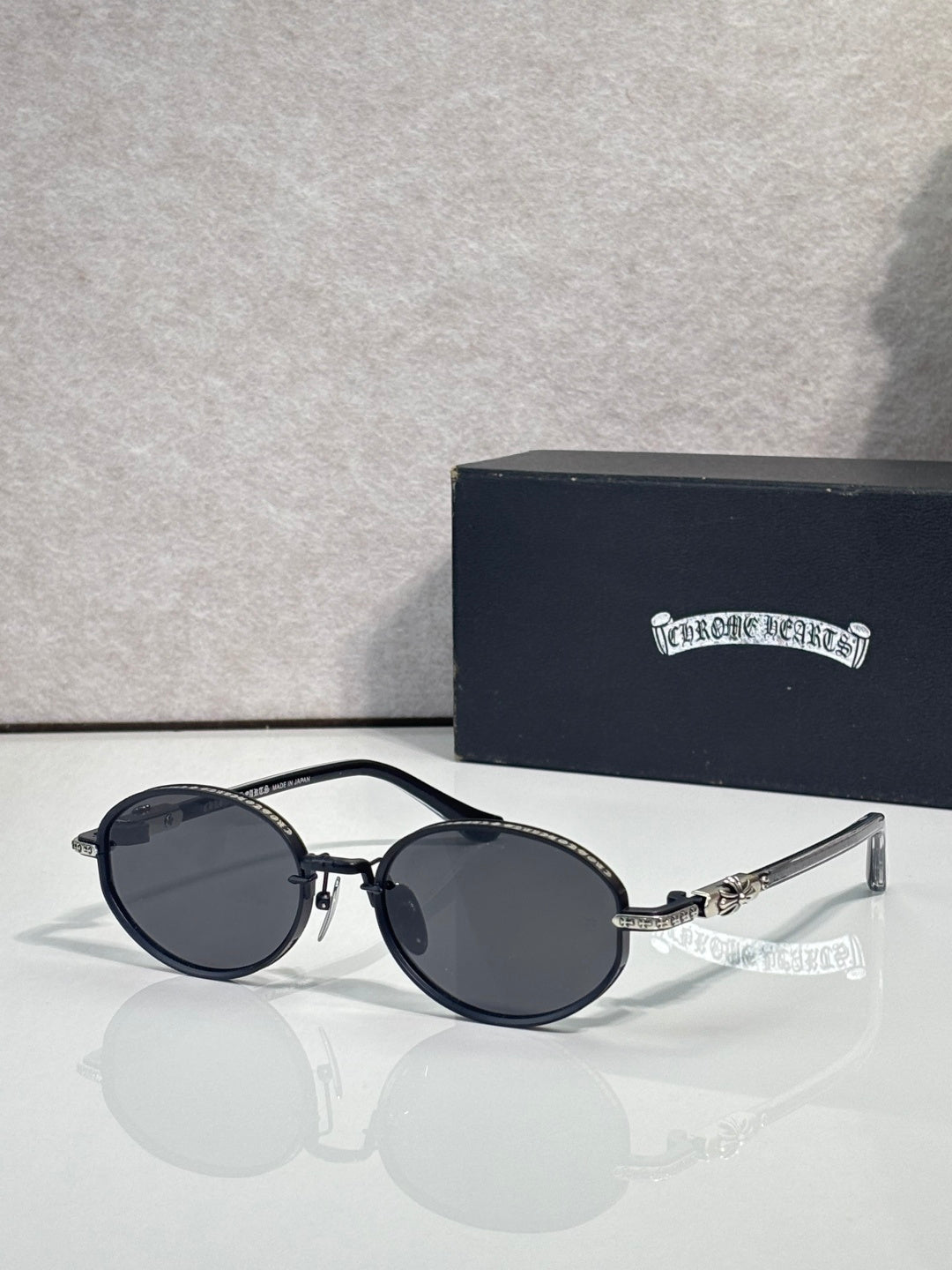 Chrome glasses with round dark lenses and black frames, clear temple arms.