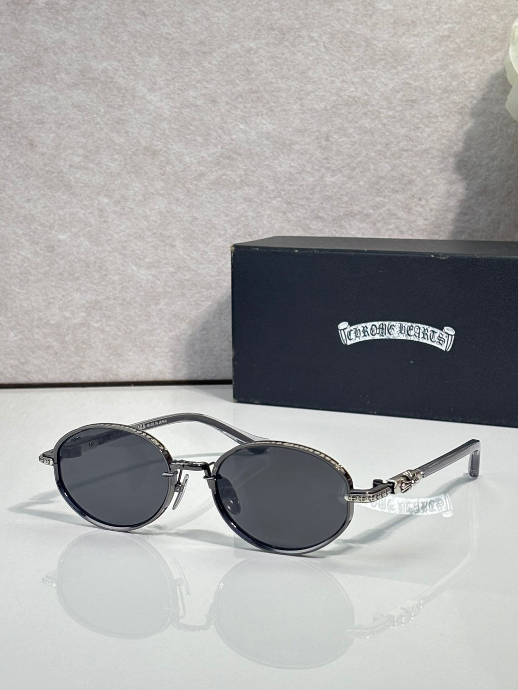 Chrome glasses with round dark lenses and black frames, clear temples.