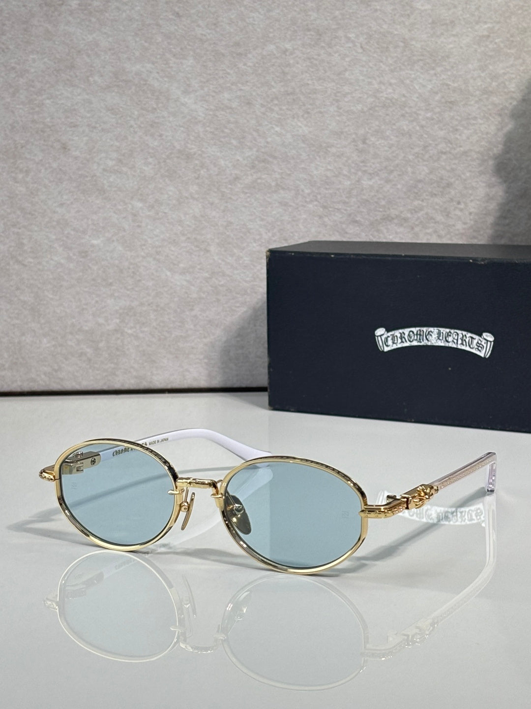 Chrome glasses with round light-blue lenses and gold-and-silver frames, clear temples.
