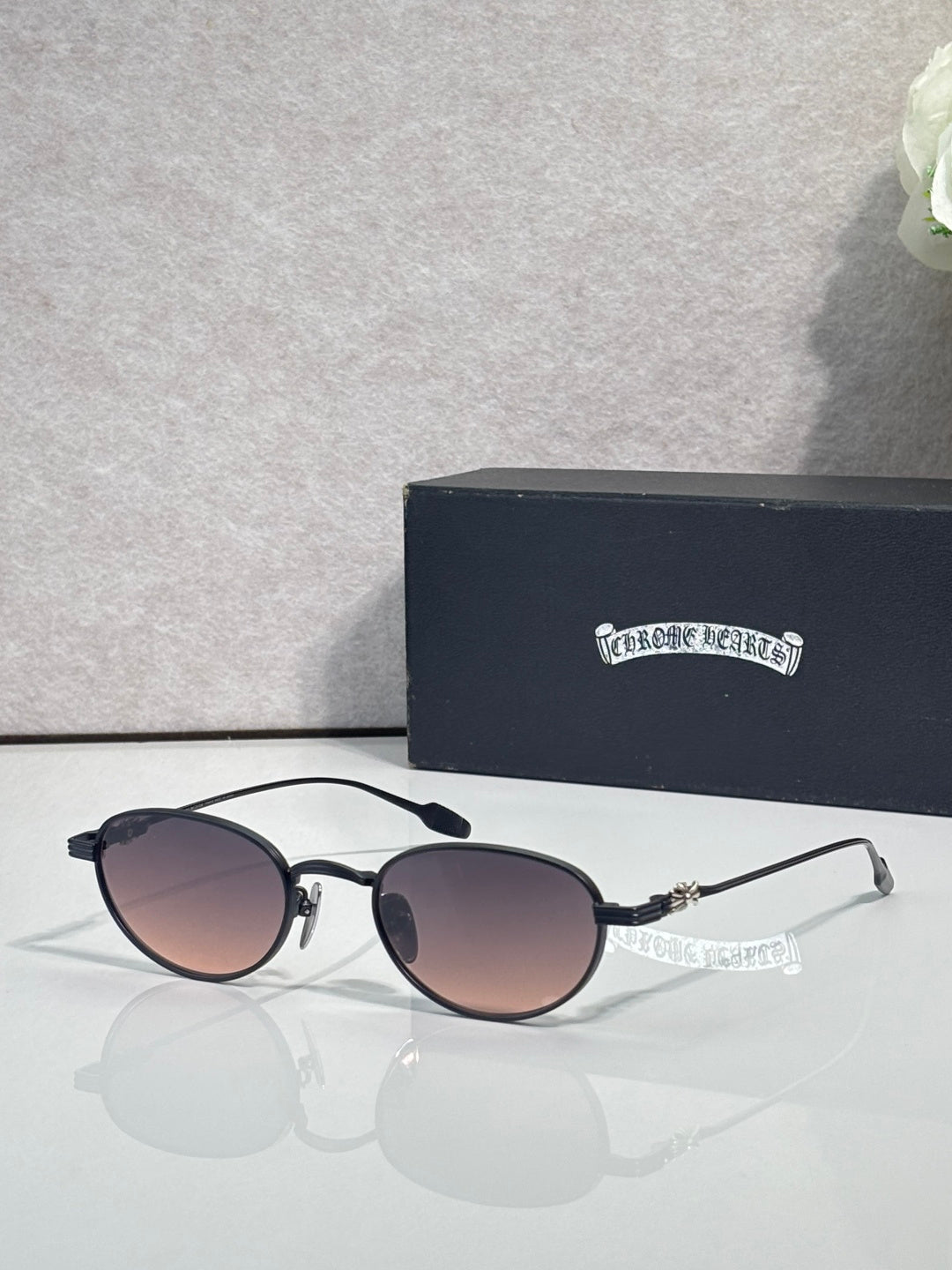 Round sunglasses with dark lenses, black frame, and chrome temple details