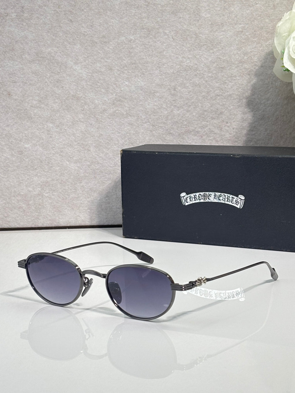 Round sunglasses with dark lenses, black frame, and decorated chrome temple tips