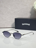 Round sunglasses with dark lenses, black frame, and decorated chrome temple tips