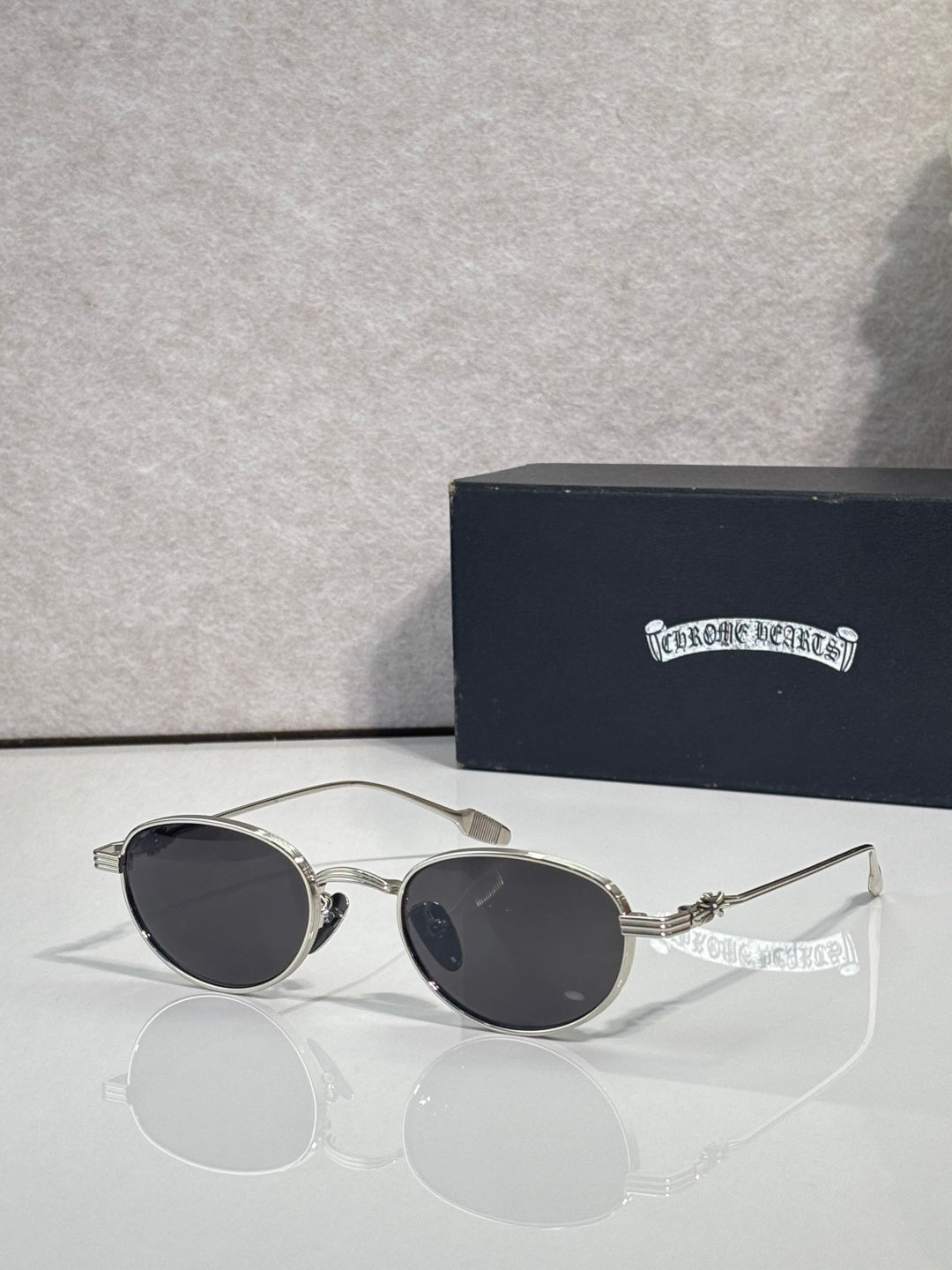 Round sunglasses with dark lenses and silver-toned frame with decorative temples