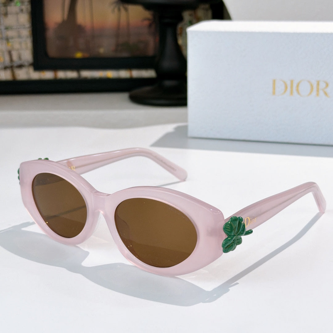 Dior sunglasses with light pink frames and brown tinted lenses, featuring a green flower detail.