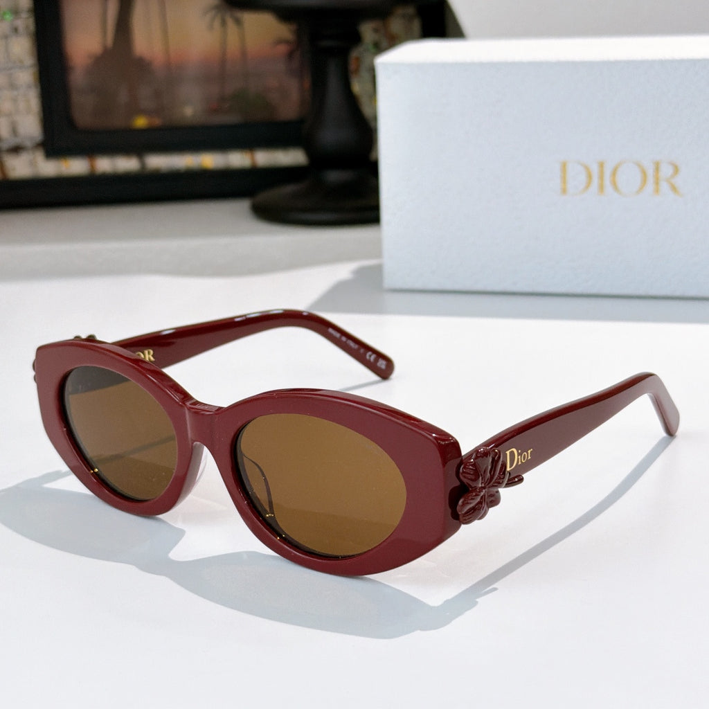 Dior sunglasses with red frames and brown tinted lenses, featuring a red flower detail.