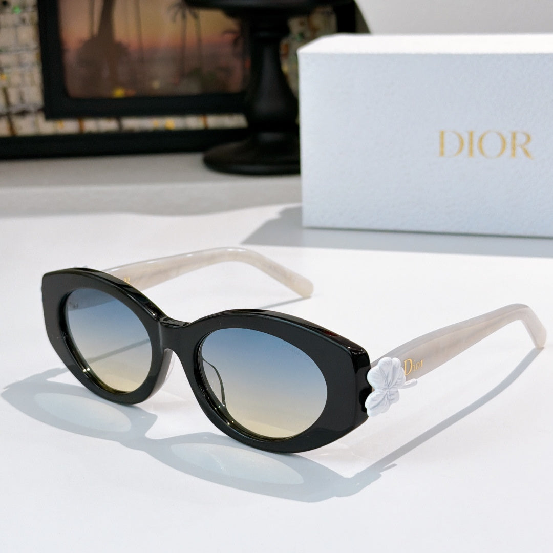 Dior sunglasses with black frames and blue tinted lenses, featuring a white flower detail.