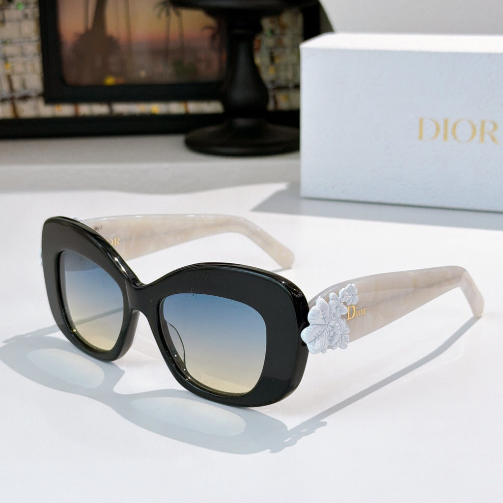 Dior sunglasses with black frames, tinted lenses, and pale blue floral temple detail