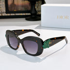 Dior sunglasses with black frames, dark lenses, and green floral temple detail