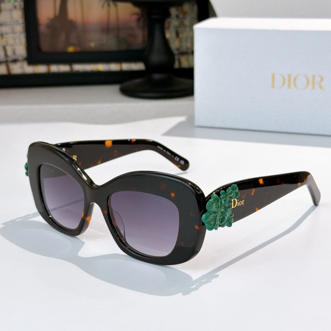 Dior sunglasses with black frames, dark lenses, and green floral temple detail