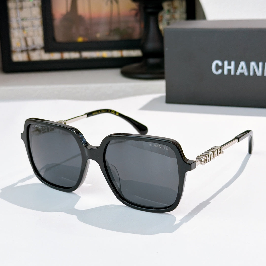 Black sunglasses with dark lenses and gold logo temple detailing
