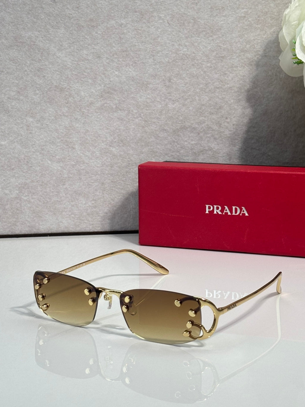 Eyeglasses by Prada with tan lenses and gold-tone frame, studded details at hinges