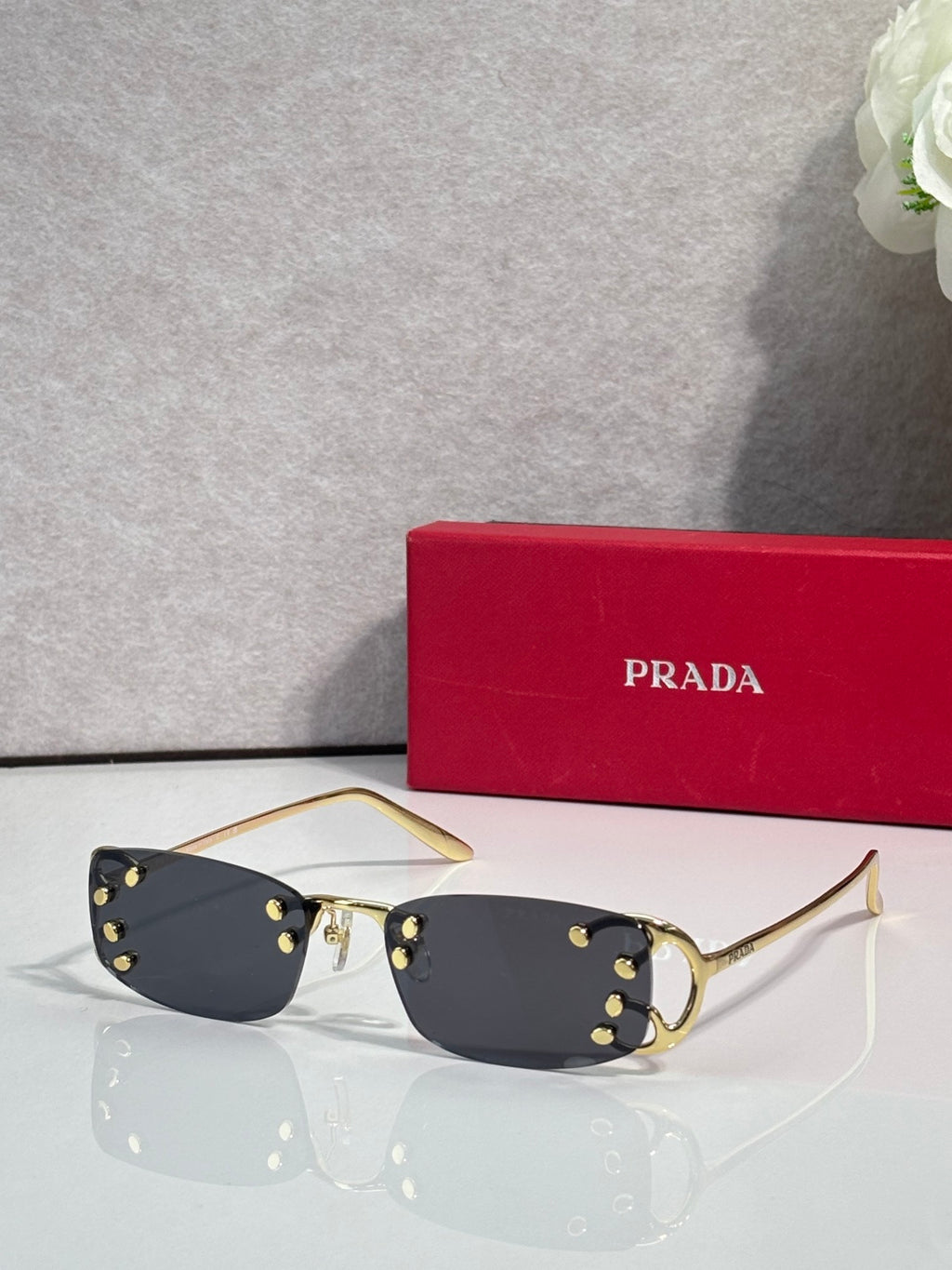Eyeglasses by Prada with dark lenses and gold-tone frame, studded detailing at hinges