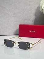 Eyeglasses by Prada with dark lenses and gold-tone frame, studded detailing at hinges